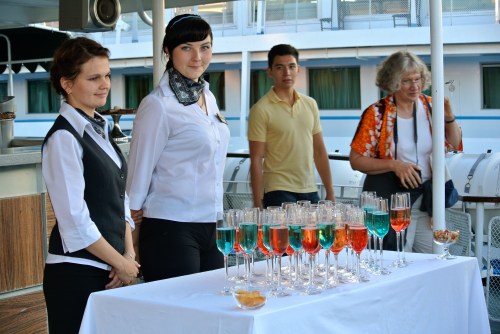 The crew offers passengers colored champagne as they depart Kizhi.